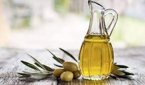 aceite de oliva en una aceitera con aceitunas sobre una mesa de madera